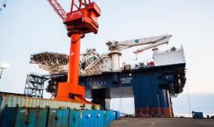 AXIS VEGA offshore drilling rig docked with large red SGL 100m crane and blue shipping containers – showcasing Almaco’s turnkey offshore accommodation systems and modular living quarters for industrial marine operations.