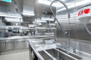Modern commercial kitchen with stainless steel sinks, industrial faucet, ovens, and modular workstations—designed for marine catering, offshore galley systems, and hygienic food preparation by ALMACO.