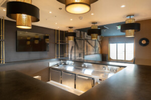 Modern kitchen with stainless steel appliances, pendant lighting, and flat-screen TV—designed for modular marine galley systems, offshore hospitality, and hygienic food preparation by ALMACO.