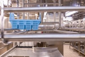 Industrial marine dishwashing area with stainless steel equipment and blue plastic rack – ALMACO galley solution