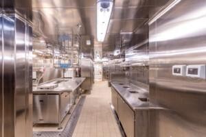 Modern stainless steel commercial galley kitchen with dual workstations, sinks, and appliances, designed for efficient food preparation in marine and offshore environments.