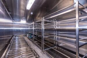 Empty industrial storage room with stainless steel shelving and reflective surfaces – clean, well-lit environment for commercial or marine supply storage.