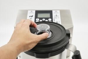 Hand adjusting lid of stainless steel food processor with control panel – ALMACO marine galley and foodservice technology solutions