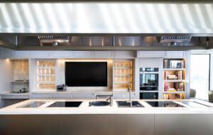 Modern galley kitchen with central island, stovetops, built-in ovens, and shelving – ALMACO premium marine hospitality and modular galley design