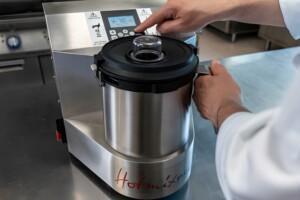 User operating HotmixPRO stainless steel kitchen appliance – digital control panel in use with safety indicators and multifunction cooking interface.